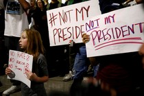 Protesters, including a young girl, hold signs reading "not my president" and "no hate, no racism, no Trump."