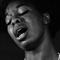 Nina Simone singing with her eyes closed, wearing a pearl necklace