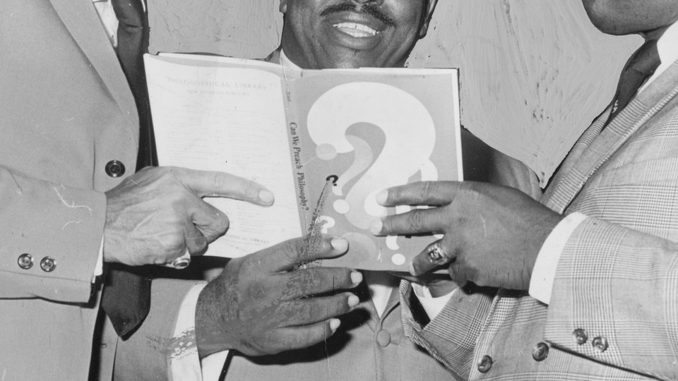 Three pairs of hands hold one book.