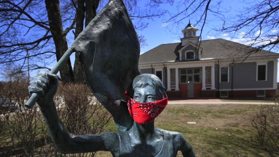 A statue of Olympic marathon gold medalist Joan Benoit Samuelson wears a red bandana mask outside the library in Cape Elizabeth, Maine
