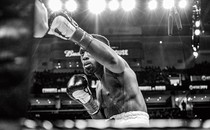 boxer making a left jab in the ring with bright lights and arena behind him