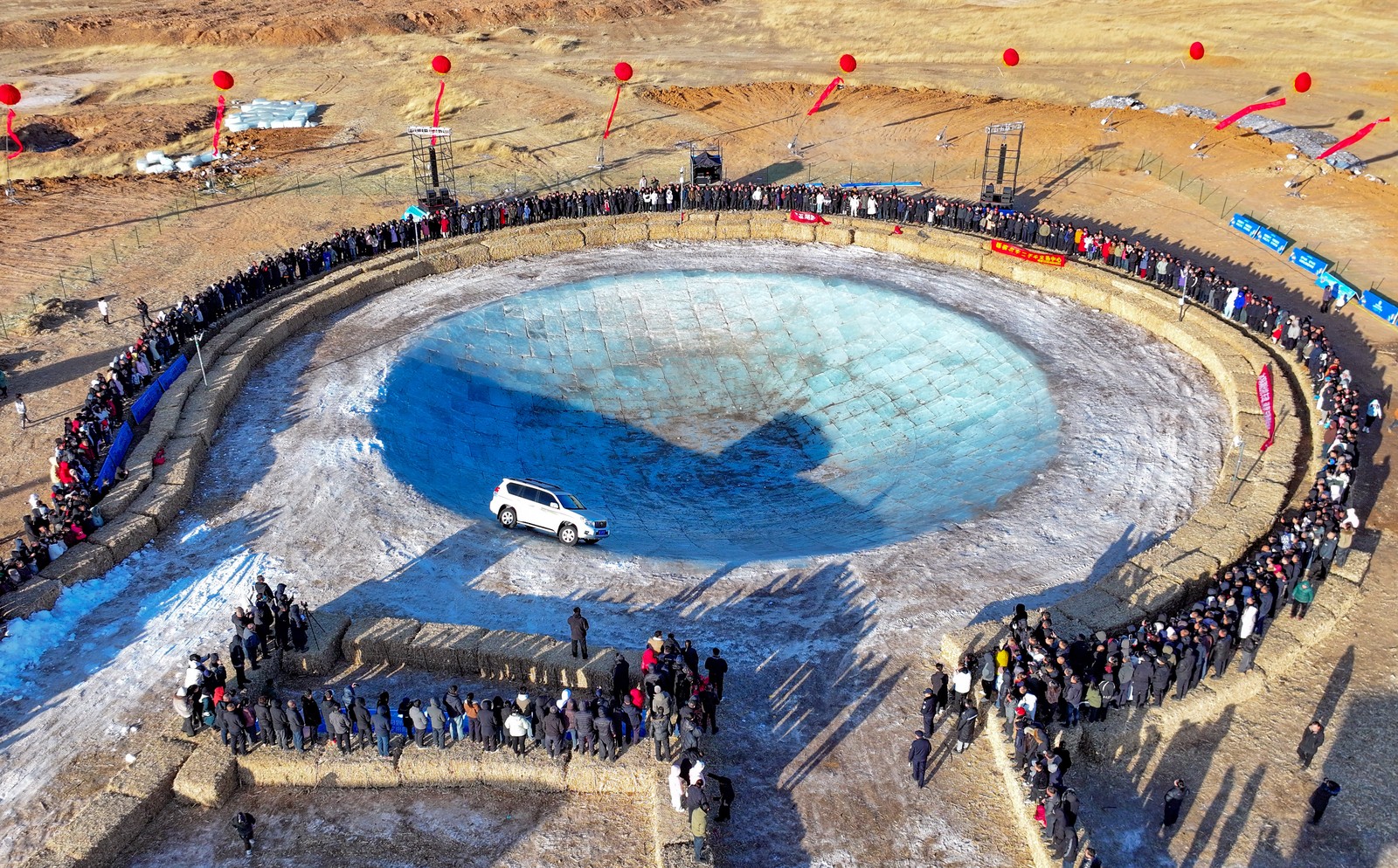 An off-road vehicle tries drifting inside a large bowl-shaped depression made from ice blocks.