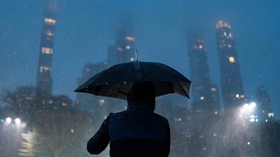 A person holds an umbrella in the wet and snowy city