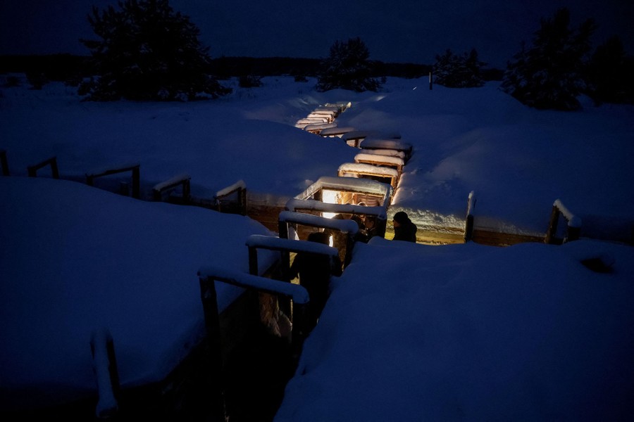 An overview of a system of trenches seen at night, in a snowy field