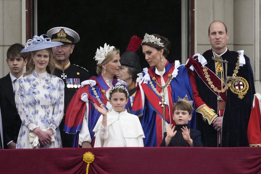 Members of the Royal Family stand on a balcony and wave.