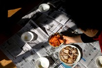 Woman placing bowel of kimchi on newspapers on the floor