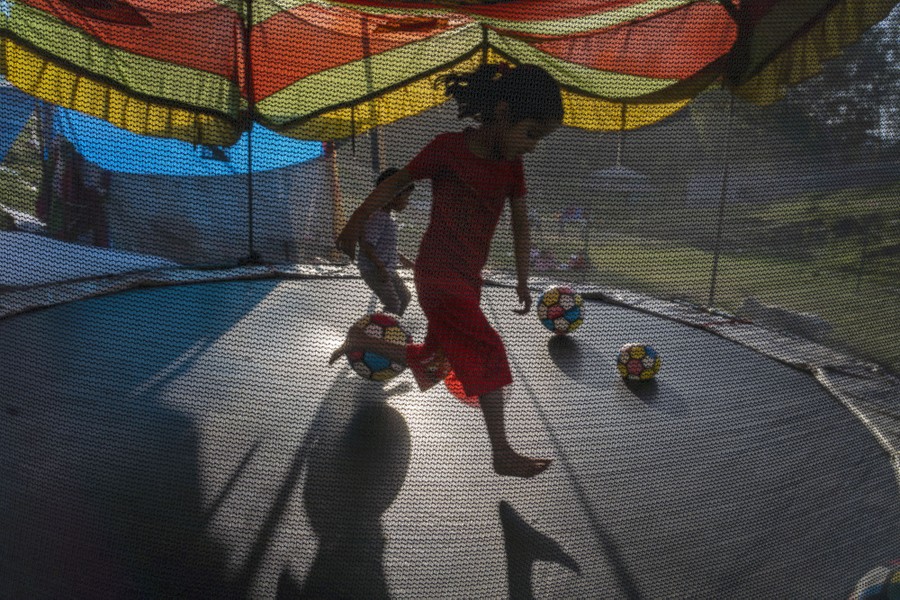A girl plays on a trampoline at a small fair.