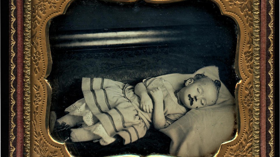 A framed black-and-white image of a deceased infant