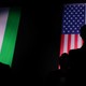 An image of two men standing in front of a U.S. flag and a Hungarian flag
