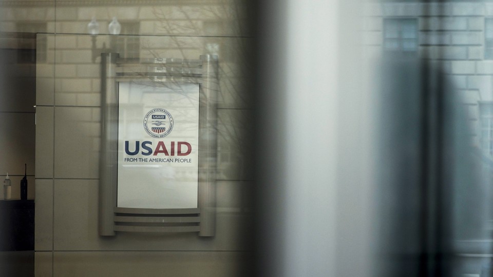 A sign at the entrance of the USAID building, as seen through glass