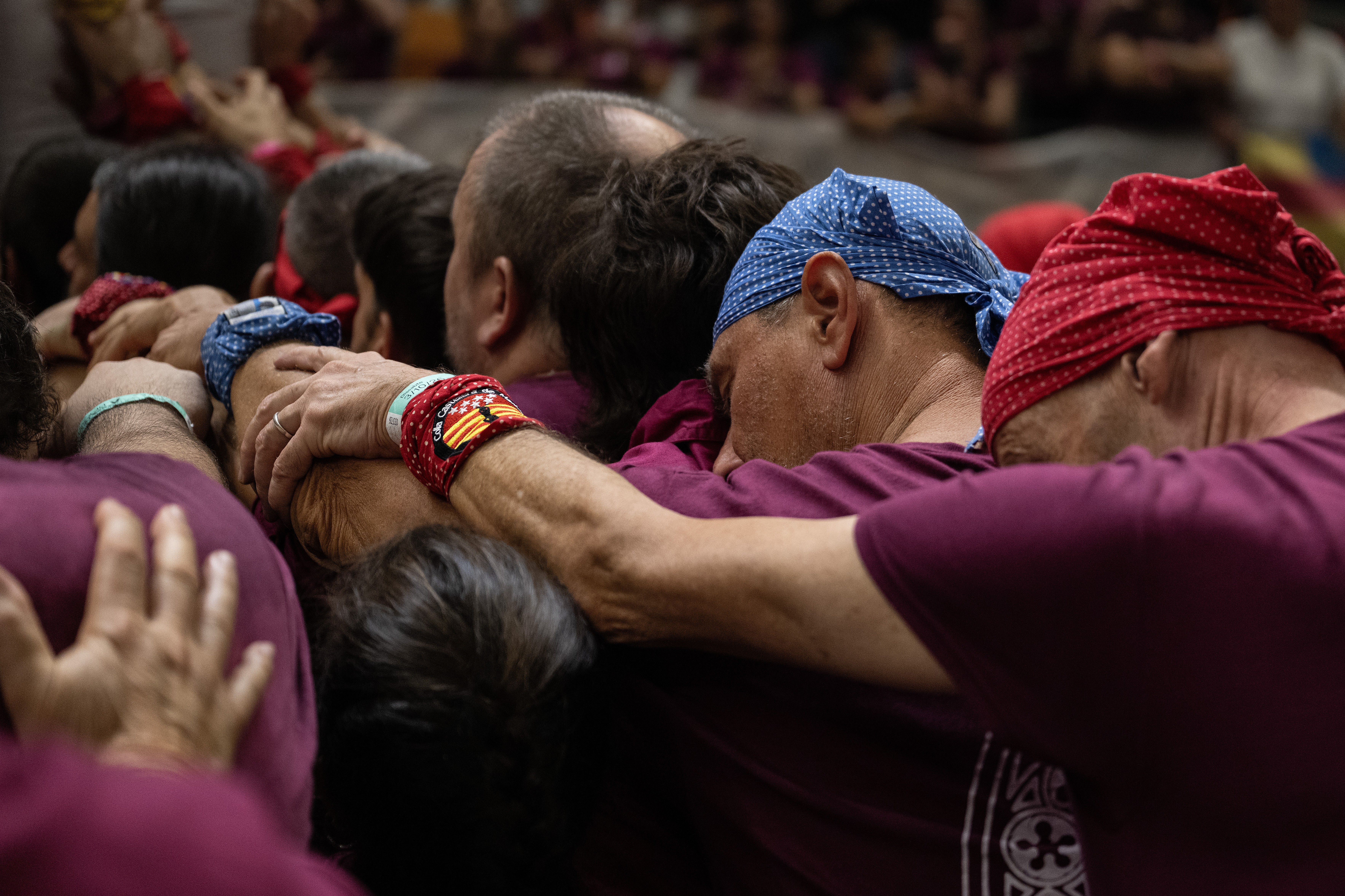 A close view of part of a larger group of people leaning on each other, supporting an unseen human tower