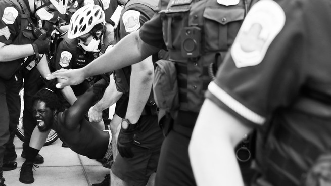 A Black Lives Matter protestor being manhandled by cops