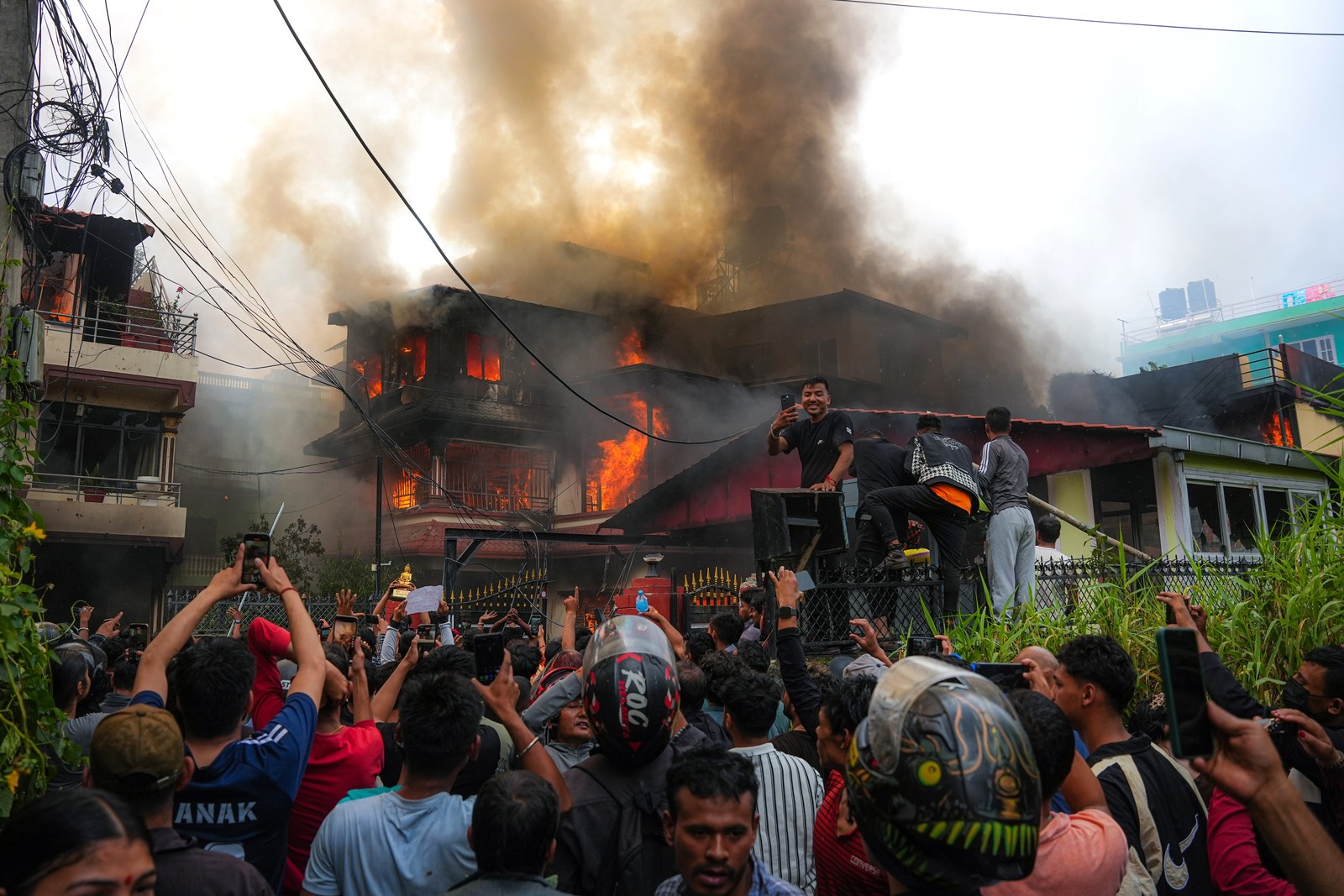 Protesters gather, and cheer outside a burning building.