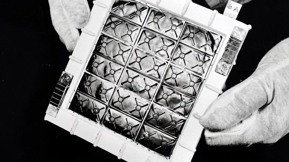 gloved hands hold a thermoelectric panel in a black and white photo