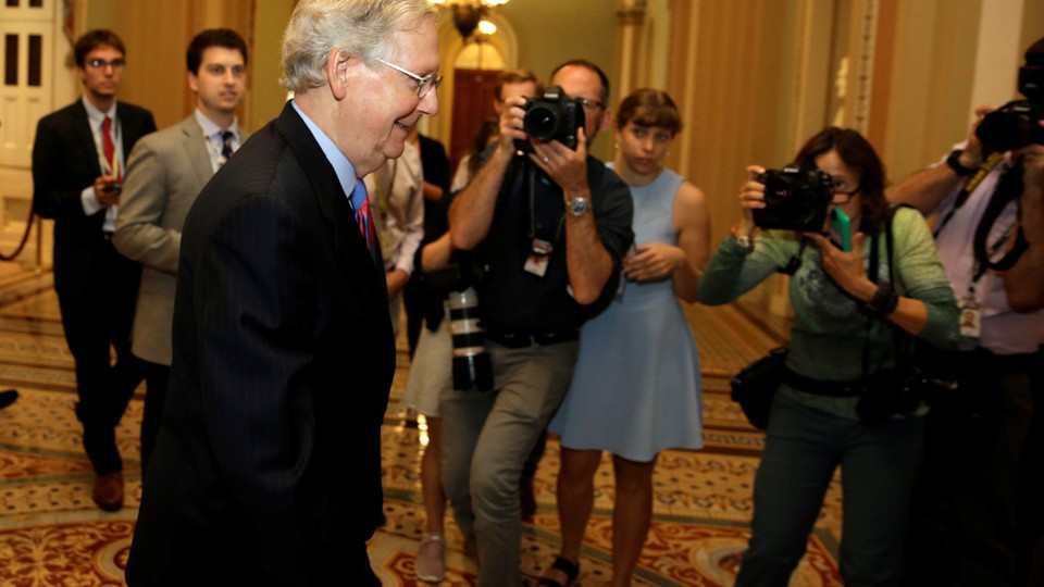 Senate Majority Leader Mitch McConnell walks down a hallway in a Capitol Hill building.