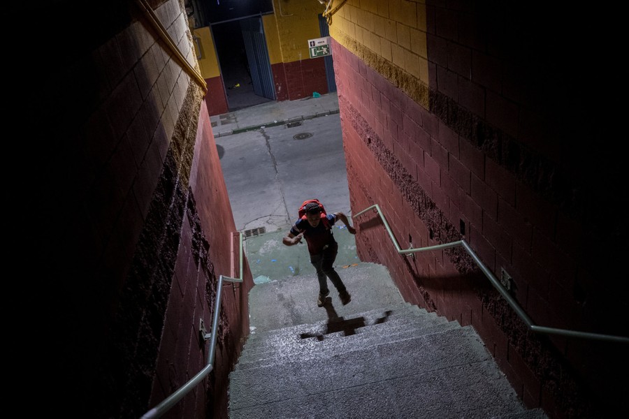 A young migrant runs up stairs in an alleyway.