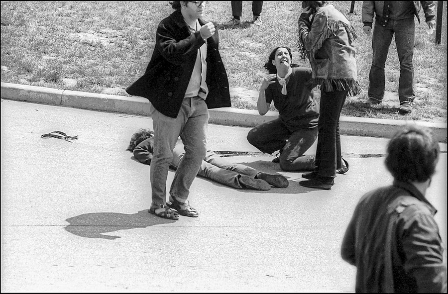 A young woman kneels over the body of a demonstrator who has been shot, as others nearby try to get help.