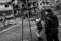 A boy plays on a swing in front of a damaged residential block in Kyiv, Ukraine.