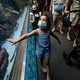 A masked girl touches an aquarium.