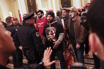 Insurrectionists inside the Capitol building, confronted by police. Man in center is wearing a QAnon T-shirt.