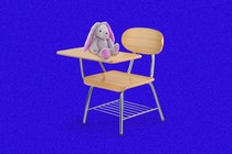 A school desk chair with a stuffed bunny placed on the writing surface