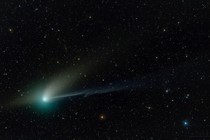 A comet against a backdrop of stars. The comet looks like a bright, greenish smudge with two different "tails."