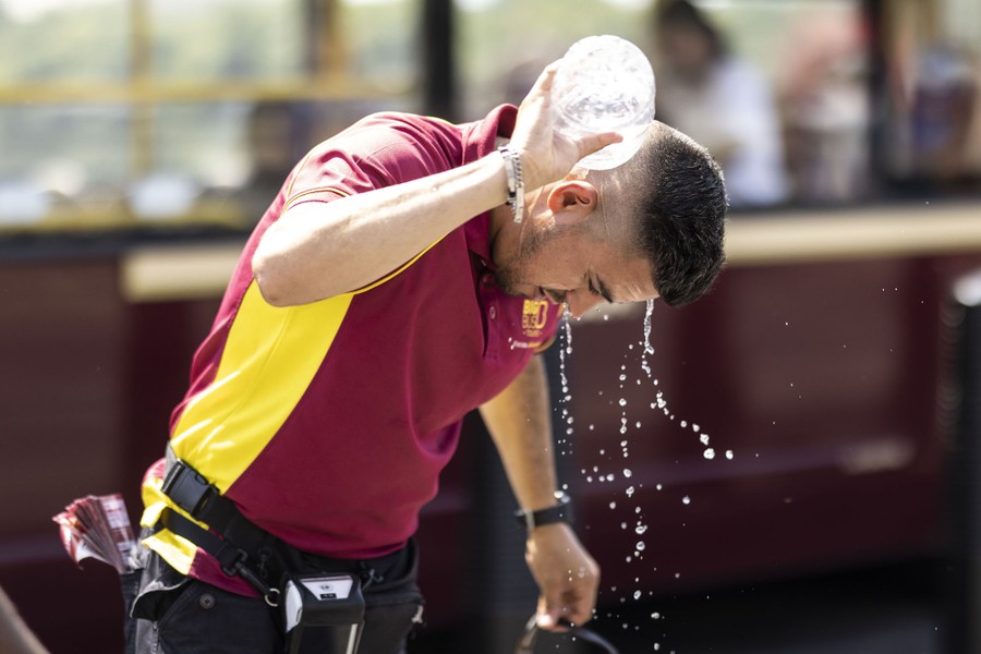 A man pours water from a bottle over his head and neck.