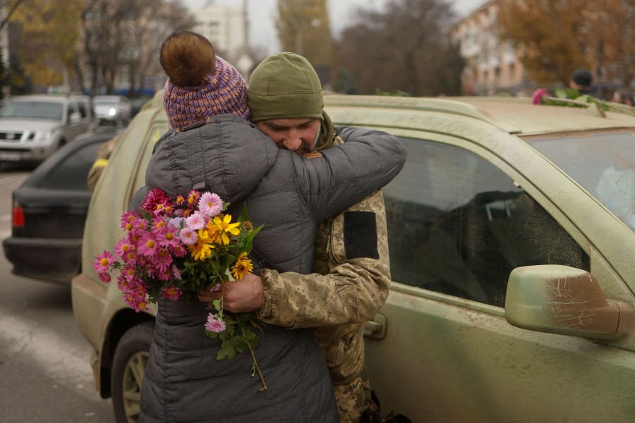 A person hugs a soldier in a city street.