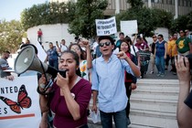 Students are seen with megaphones and signs, protesting. 