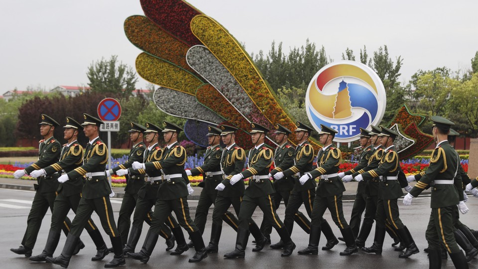 Chinese paramilitary policemen walk past a display ahead of Beijing's Belt and Road Forum.
