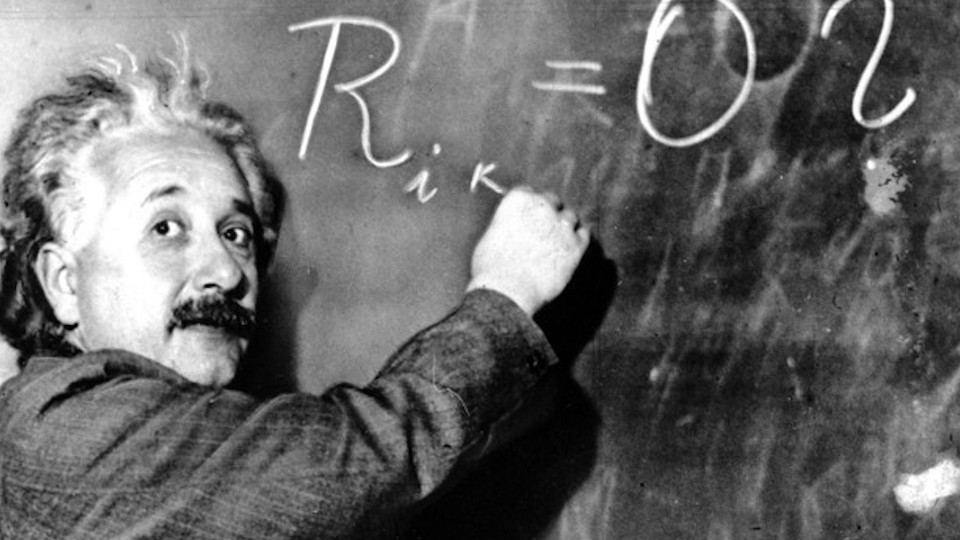 Photograph of Albert Einstein writing a formula on a blackboard