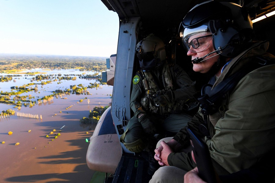People view flooded areas from inside a helicopter.