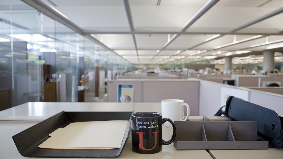 A mug sits on a desk in an office. The mug reads "We can't spell success without U."