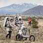 NASA astronauts push a tool cart loaded with lunar tools through the San Francisco Volcanic Field north of Flagstaff, Arizona, as they practice moonwalking operations for Artemis III.