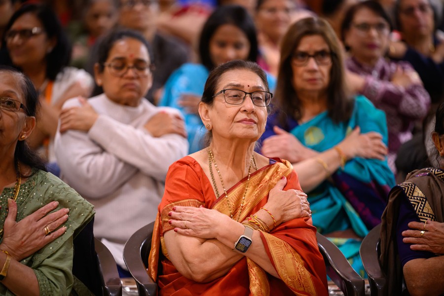 People sit together with their arms crossed during a ceremony.