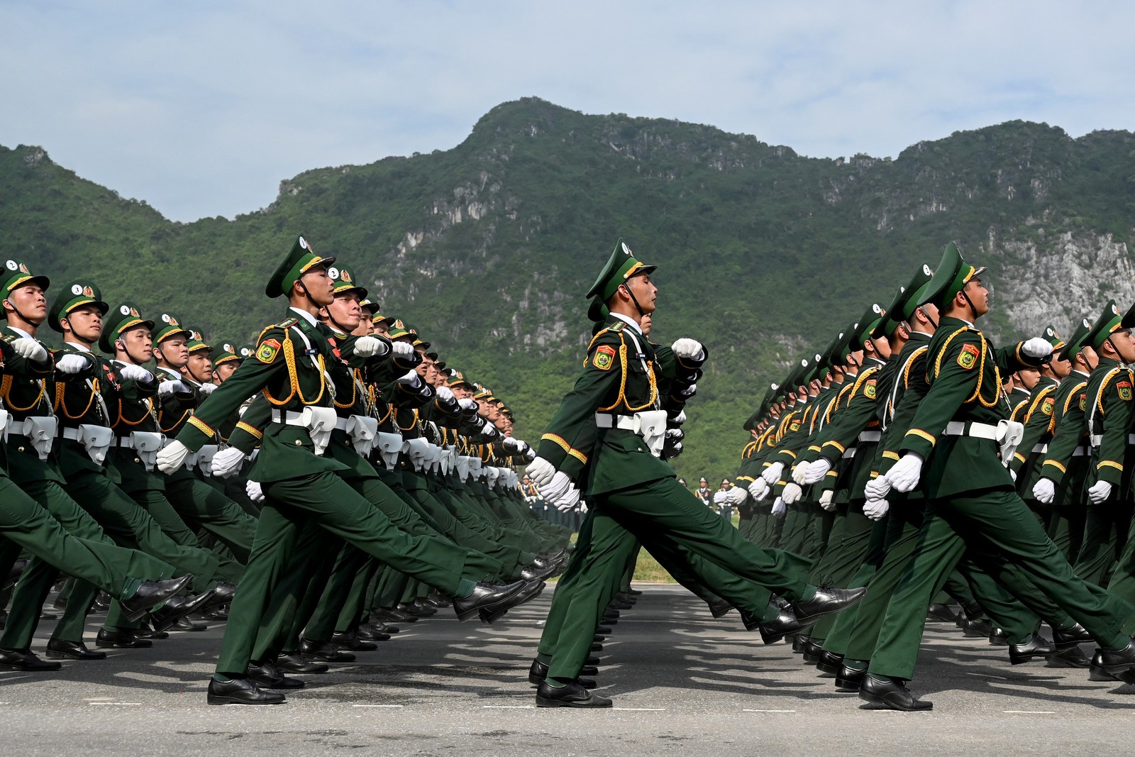 Rows of soldiers in dress uniform walk in unison during a parade.