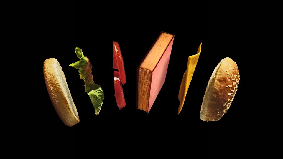 A book floats in the air between two buns, a piece of lettuce, two tomato slices, and American cheese.
