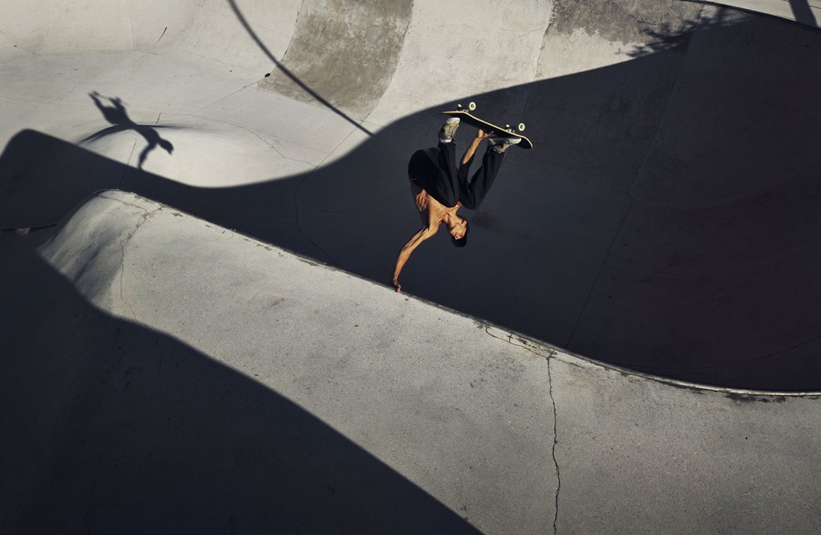 A skateboarder practices in a concrete skate park.