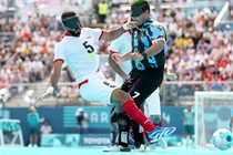 Two football players wearing blindfolds collide while chasing the ball during a match at the Paralympic Games.