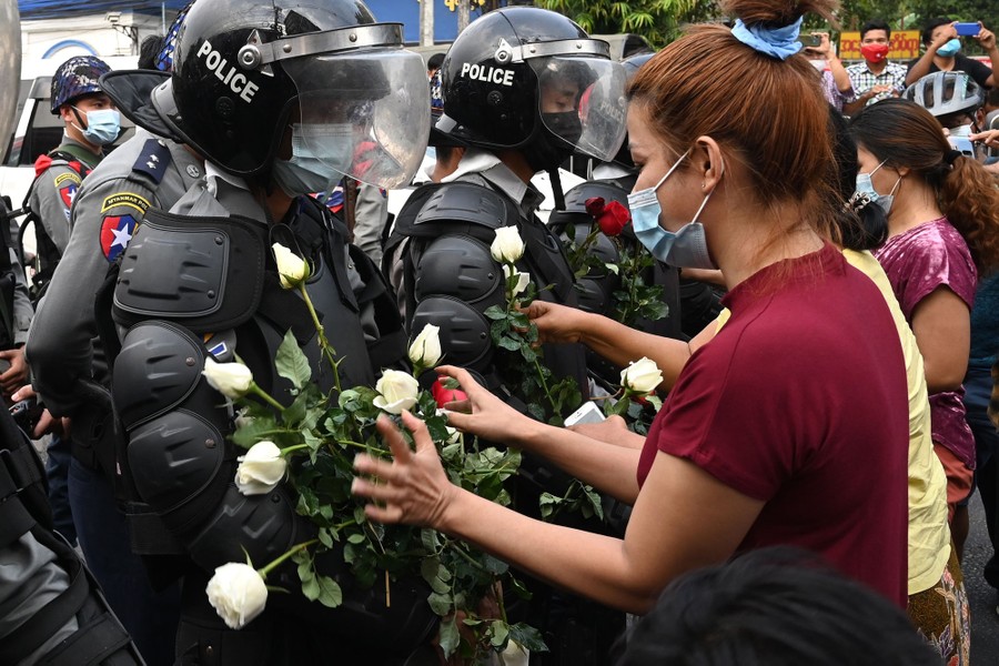 Protesters give flowers to riot police wearing full gear.