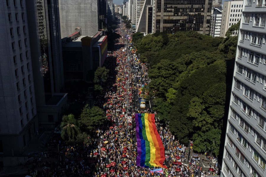 A Pride parade on a city street, featuring a long rainbow flag