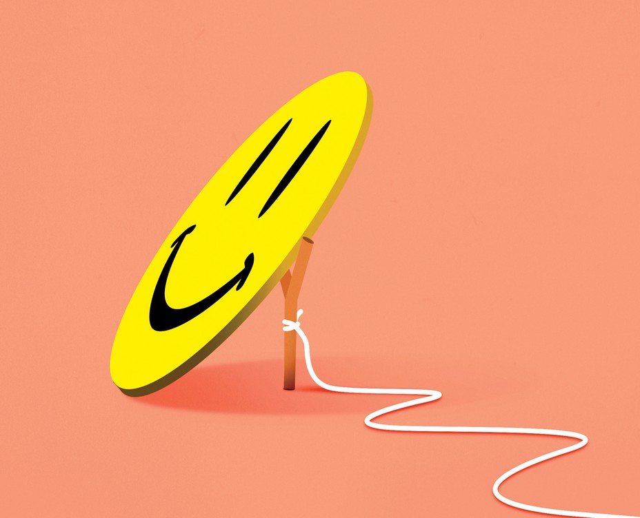 a flat, black and yellow happy face leans against a stick with a rope tied to it to make a trap
