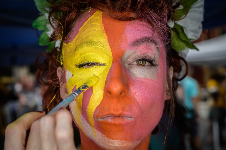 A person has their face painted in bright colors.