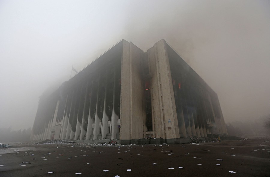 A large concrete building is seen scorched and smoking.
