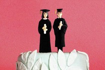 A wedding-cake topper with two people in graduation gowns