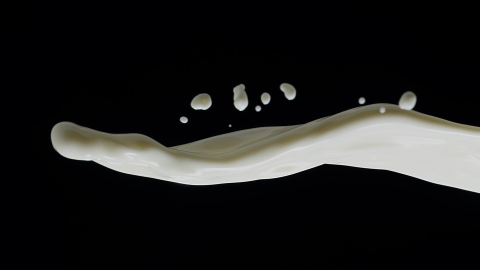 a stream of white liquid splashing onto a dark background from the right side of the image