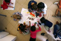 An overhead view of six pre-schoolers coloring.