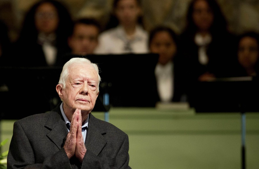Jimmy Carter stands before a Sunday-school class, clasping his hands together.