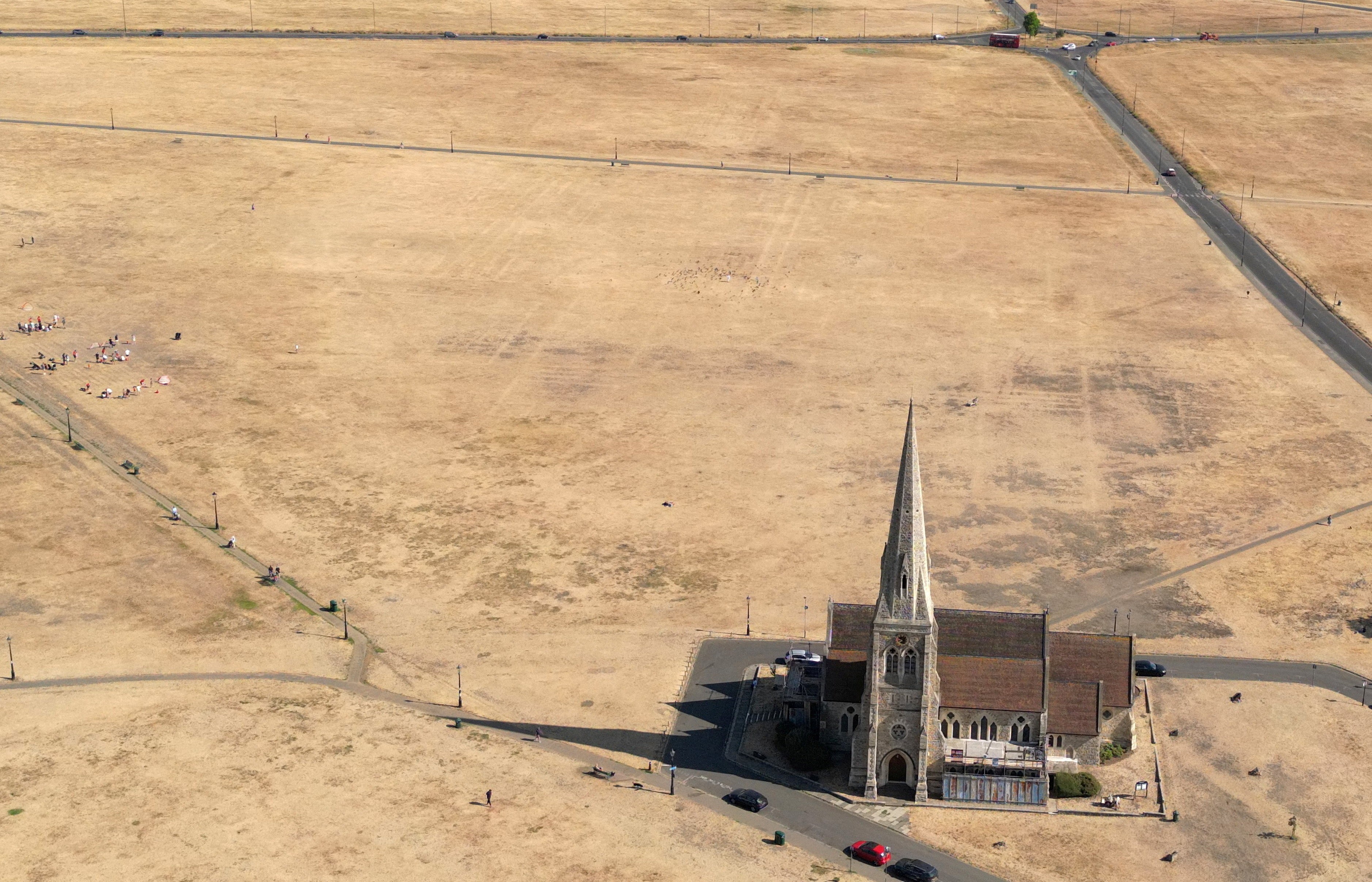 A drone view shows a church surrounded by parched grassland.