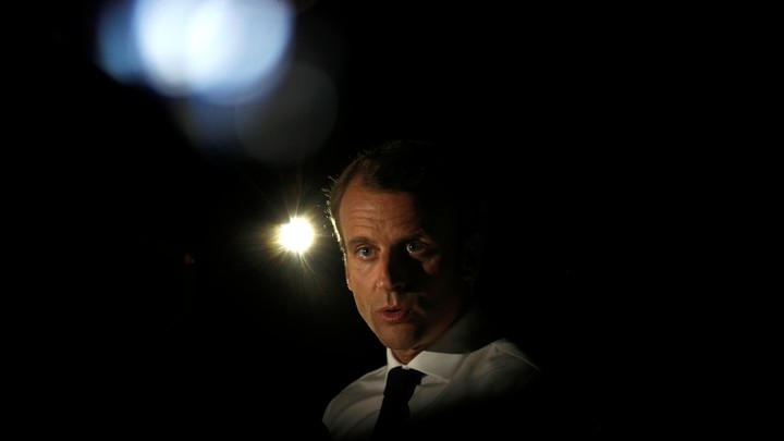 President Emmanuel Macron talks with lights in the background.